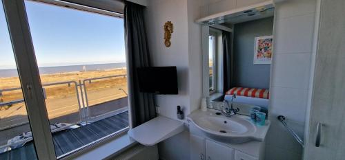 a bathroom with a sink and a view of the beach at Hotel B&B Seahorse in Katwijk