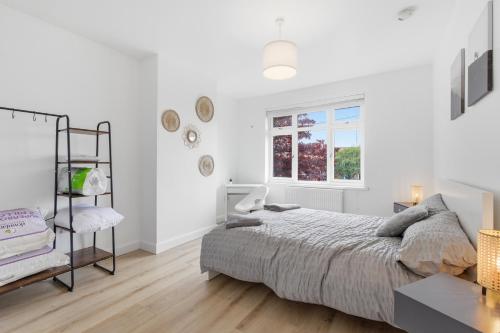 a white bedroom with a bed and a window at Large, Bright 4 Bed Home with Garden in Kenton