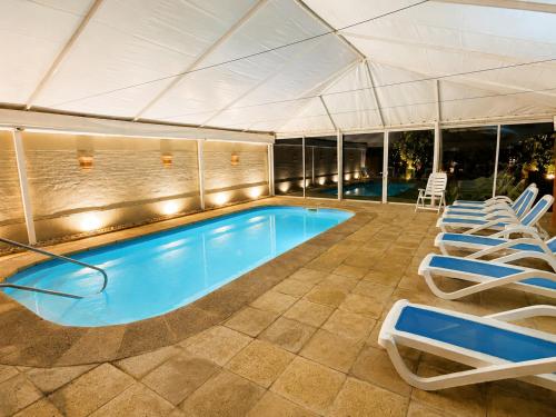 a swimming pool with chairs and a tent at Hotel Ajax in Punta del Este