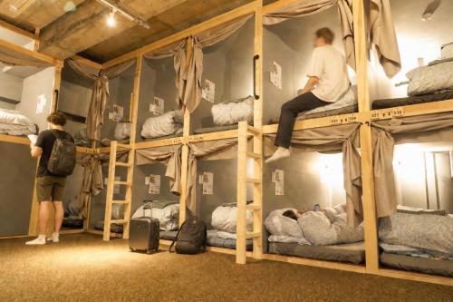 two people are climbing on bunk beds in a room at MATSUMOTO CASTLE hostel in Matsumoto