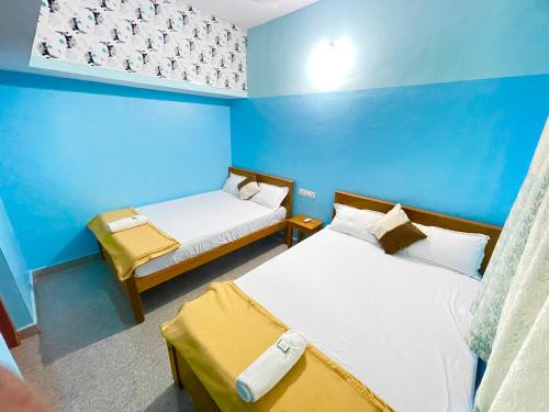 a room with two beds and a blue wall at R J Homestay in Māvalli