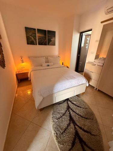 a bedroom with a large white bed and a rug at ARAD-DEAD SEA BASHIRIS PLACE in Arad