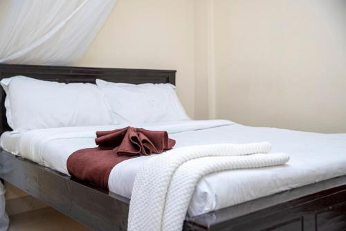 a bed with white sheets and a brown towel on it at ST Augustine Hotel Ltd in Kisumu