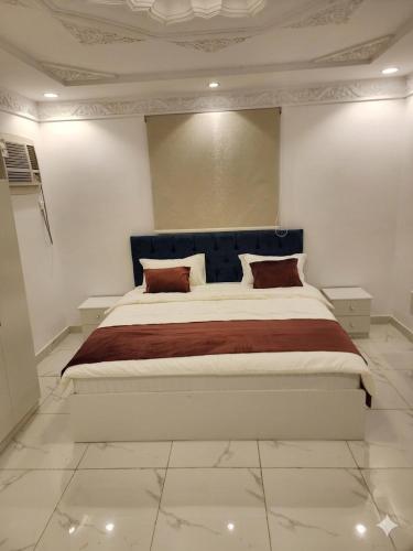 a bedroom with a large bed with a blue headboard at غرفتين وصالة النبلاء in Medina