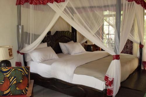 a bedroom with a canopy bed with white curtains at Mrëmbo Boutik Hôtel in Ruhengeri