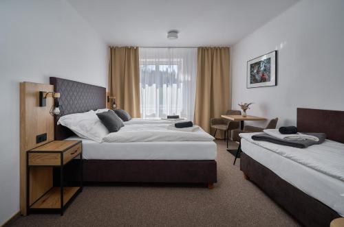 a hotel room with two beds and a table at Hotel Popel in Stachy