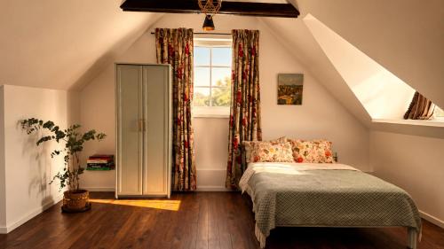 a attic bedroom with a bed and a window at Gedvilų sodyba in Kelmė