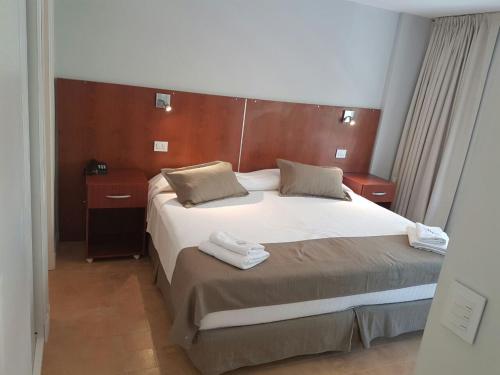 a bedroom with a large bed with two towels on it at Hotel Novi in Mar del Plata