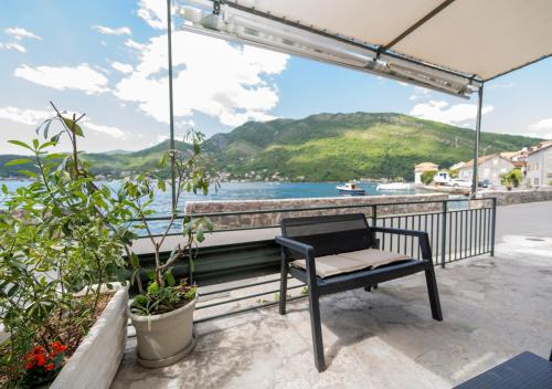 a bench sitting on a balcony overlooking a body of water at Seafront Stone House Maxim in Tivat