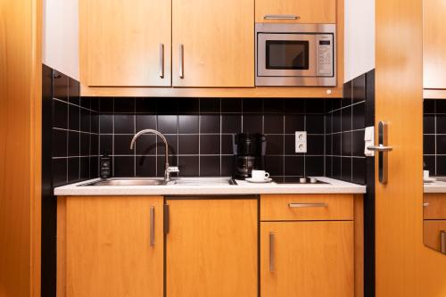 a kitchen with wooden cabinets and a sink and a microwave at historic Apart in Erlangen