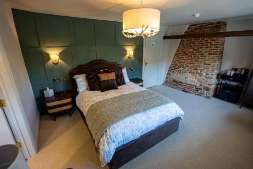 a bedroom with a large bed and a brick wall at The Huntsman in Norwich