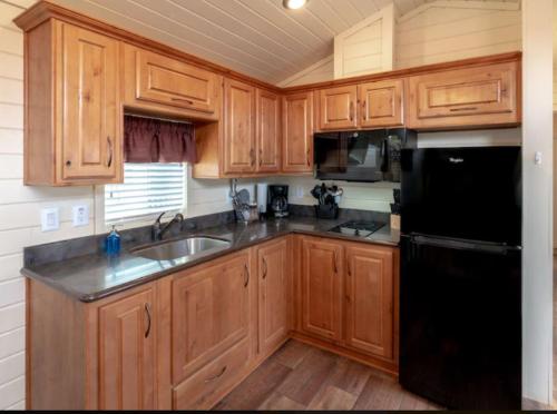 a kitchen with wooden cabinets and a black refrigerator at 49er Village in Plymouth