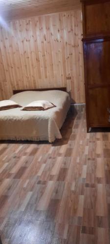 a bedroom with a bed and a wooden floor at Dogurashi Turbaza in Tsʼageri