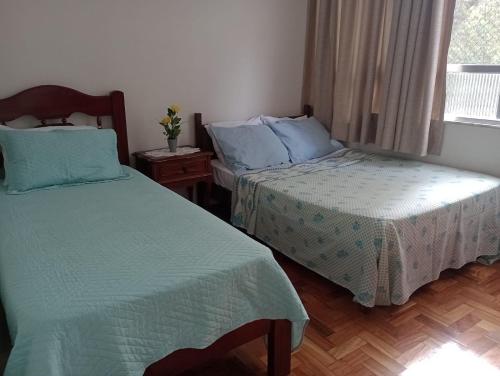 a bedroom with two beds and a window at Apto Clássico, Centro de Friburgo, em frente à Pça Getúlio Vargas e pertinho do Teleférico e da Pça Suspiro - Muito bem equipado - Aquecedor in Nova Friburgo