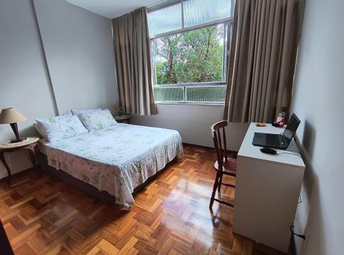 a bedroom with a bed and a desk with a laptop at Apto Clássico, Centro de Friburgo, em frente à Pça Getúlio Vargas e pertinho do Teleférico e da Pça Suspiro - Muito bem equipado - Aquecedor in Nova Friburgo