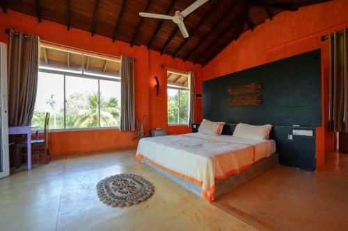 a bedroom with orange walls and a bed in a room at Singhe House in Dickwella