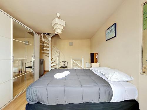 a bedroom with a large bed and a spiral staircase at Maison de bourg - Charmante & Authentique , PLAUZAT in Plauzat