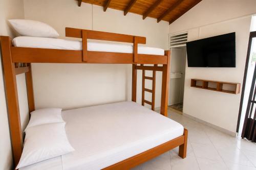 two bunk beds in a room with a flat screen tv at Hotel Manglares in Capurganá