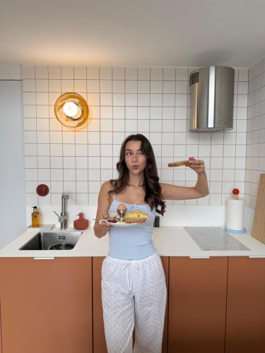 a woman standing in a kitchen holding a plate of food at Hvile in Kleszczyn