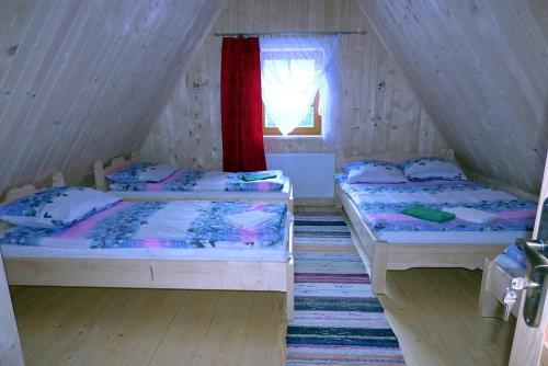 two beds in a attic bedroom with a window at Domek Góralski Suche in Suche