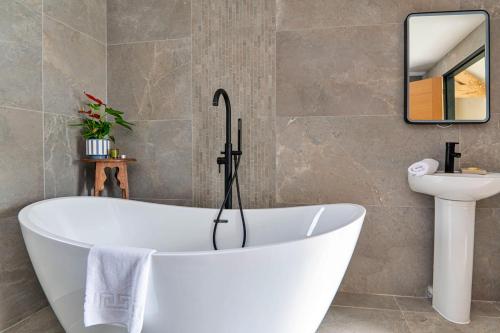 a bath tub in a bathroom with a sink and a mirror at Finest Retreats - Cae Rhug in Llanuwchllyn