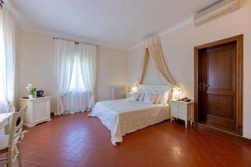 a bedroom with a white bed and two tables and windows at Tenuta Quadrifoglio in Gambassi Terme