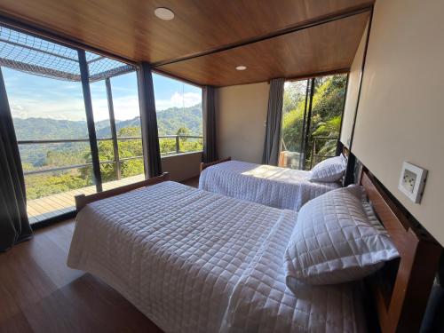 two beds in a room with large windows at Payara Experience in La Vega