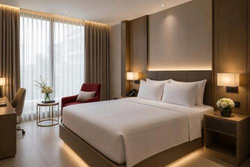 a bedroom with a large white bed and a red chair at Lagoon Beach Of The Arena Cam Ranh - Free room upgrade in Cam Ranh International Airport