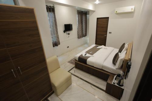 a bedroom with a bed and a door with a chair at Hotel Pearl -Jaipur Pink City Centre in Jaipur