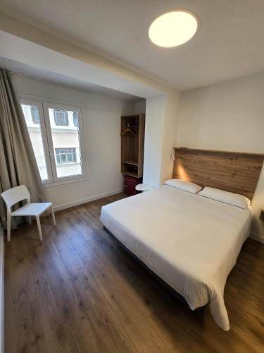 a bedroom with a large white bed and a window at B&H Boreal in Burgos