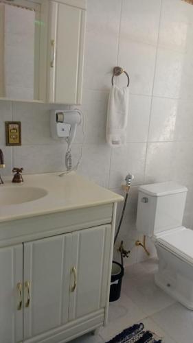 a white bathroom with a sink and a toilet at Apartamento A 43 Flat Centro in Mogi das Cruzes
