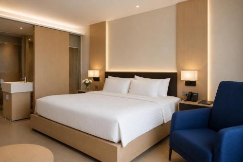a bedroom with a large white bed and a blue chair at Lagoon Beach Of The Arena Cam Ranh - Free room upgrade in Cam Ranh International Airport
