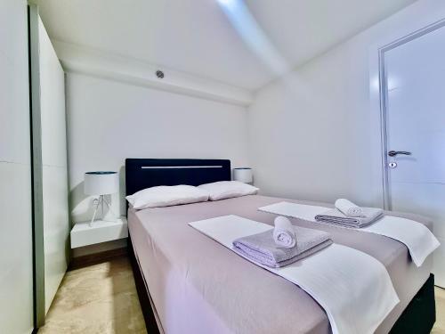 a white bedroom with two beds with towels and a mirror at Mini Lea in Jadranovo