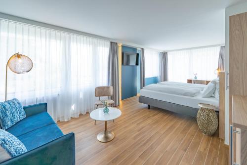 a hotel room with a bed and a couch at Hotel-Restaurant Seegarten-Marina in Spiez