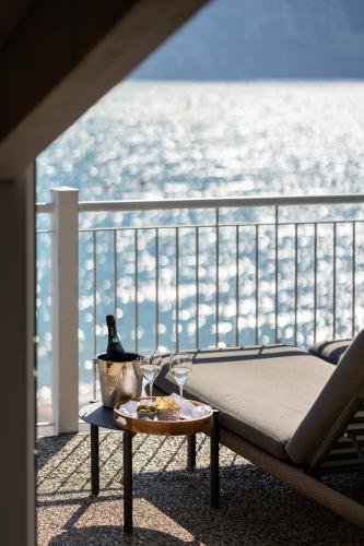 a balcony with a bed and a table with wine glasses at Hotel Baia Azzurra - Lake Front in Nago-Torbole
