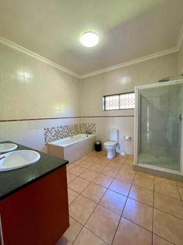 a bathroom with a tub and a toilet and a sink at Emmanuel Guest Villa in Thabazimbi