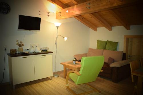 a living room with a green chair and a couch at Apart Dominika in Ried im Oberinntal