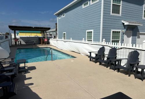 a swimming pool with chairs next to a house at The Beach Peach in Port Aransas