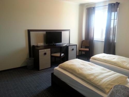 a hotel room with two beds and a desk with a television at Hotel Helena in Neu Wulmstorf