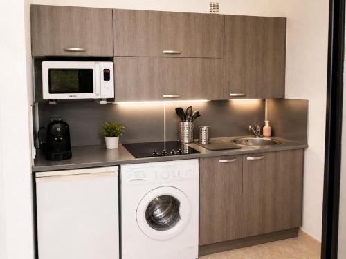 a kitchen with a washing machine and a microwave at Dramont Getaway in Saint-Raphaël