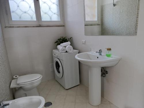 a bathroom with a toilet a sink and a washing machine at Home among the olive trees in Tivoli