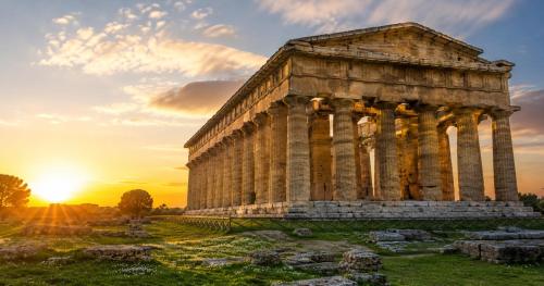 an ancient temple with the sunset in the background at Medea Beach Resort - Cultural Stay near Amalfi Coast & Paestum in Paestum