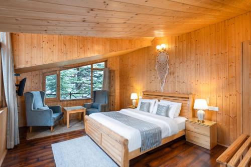 a bedroom with a bed and two chairs in a room at The Pine Chalet Manali in Manāli