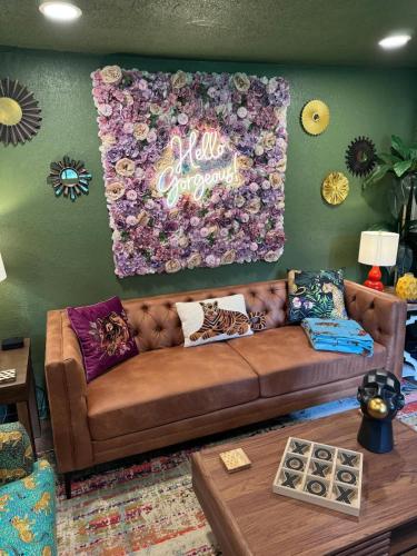 a living room with a brown couch with flowers on the wall at Kitschy Kottage in Expansion