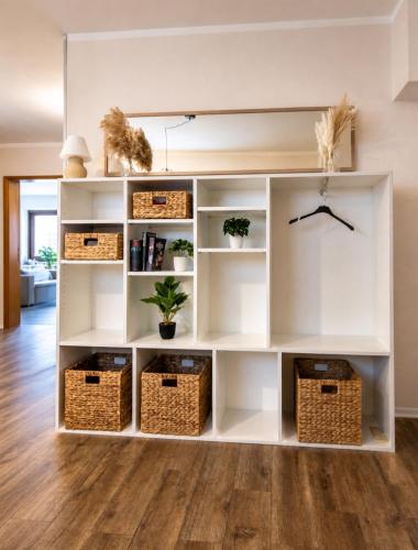 a white book shelf in a living room with baskets at FeWo Prinzregent - große Zentrale Wohnung, ideal für Gruppen & Familien in Bad Kissingen