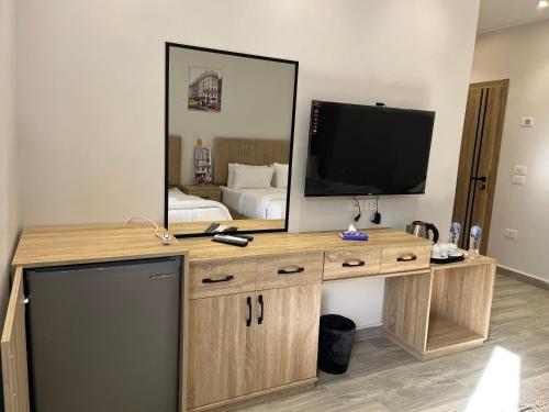 a room with a desk with a television and a bed at Saloumy pyramids hotel in Nazlat as Sammān