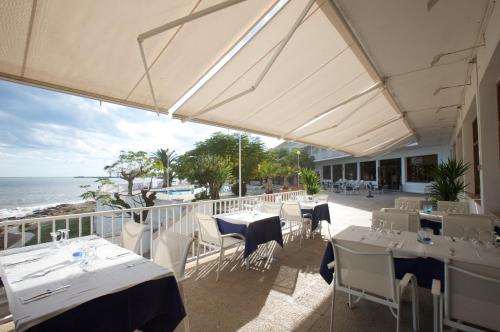 a restaurant with tables and chairs and the ocean at Carlos III in Sant Carles de la Ràpita