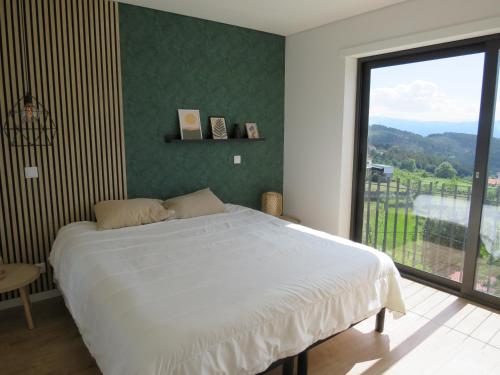 a bedroom with a large bed and a large window at Villa Paioryna - Moradia num local tranquilo in Vila Verde