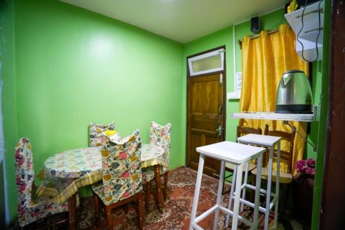 a dining room with green walls and a table and chairs at Dixit Homestaay & Hostel in Darjeeling