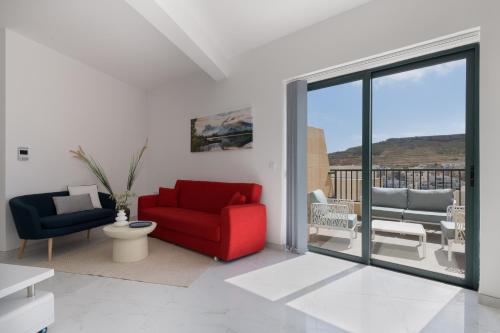 a living room with two chairs and a sliding glass door at Jacuzzi Penthouse with Large Terrace & Views in Marsalforn